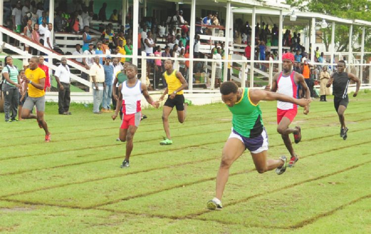 Kevin Abbensetts (right) dips at the 100m finish line in the Youth Club boys’ 100m heats yesterday afternoon ahead of sprint sensation Tevin Garraway (second left). (Orlando Charles photo)