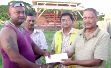 A representative of the East Canje Reunion and Family Fun Day Group presenting the US$1,000 cheque to a member of the Reliance Crematorium Committee