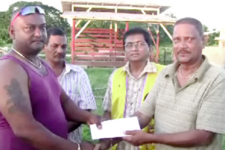 A representative of the East Canje Reunion and Family Fun Day Group presenting the US$1,000 cheque to a member of the Reliance Crematorium Committee