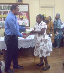 Minister of Culture, Youth and Sports Dr. Frank Anthony (left) hands over a cheque to a representative of one of the villages (right)   