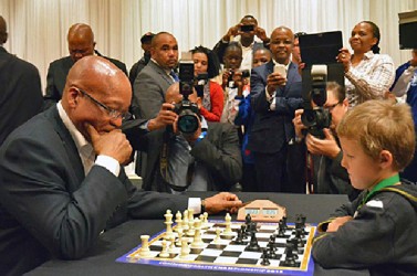 The President of South Africa Jacob Zuma plays a friendly 20-minute chess game with a five-year-old boy, Keagan Rowe. The occasion was the 2013 Commonwealth Championship that was held in Port Elizabeth, South Africa, on the occasion of the 95th birthday of Nelson Mandela. There were 900 participants from 29 countries. In his address to declare open the tournament, President Zuma referred to a time when he was a political prisoner on Robben Island, and himself and colleagues, including Mandela, fashioned chess pieces from soap and driftwood and crafted makeshift boards to play the royal game. Garry Kasparov also attended the tournament and engaged in celebrations for Nelson Mandela on his birthday on July 18.