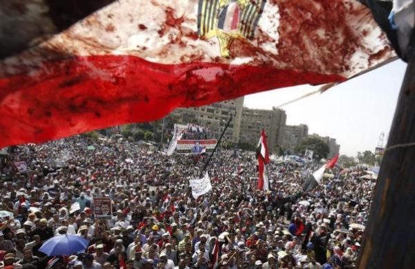 An Egyptian flag stained with blood flutters over members of the Muslim Brotherhood and supporters of deposed Egyptian President Mohamed Mursi as they shout slogans during a protest outside Raba El-Adwyia mosque in Cairo July 8, 2013, following clashes in front of the Republican Guard headquarters.
REUTERS/Mohamed Abd El Ghany