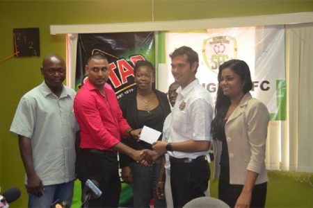 Slingerz FC Financial Director Aswell Mohabir receives the sponsorship cheque from Stag Beer Brand Manager John Maikoo while club PRO Mark Young (extreme left), NAWF President Vanessa Dickenson (centre), tournament coordinator Colin `BL’ Aaron (right) and Ansa McAl PRO Darshanie Yussuf (extreme right) look on.