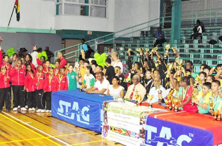 From left GTTA President Godfrey Munroe, GT&T Brand Manager Nicola Duggan, Administrator of the National Sports Commission, Gervy Harry, Director of Sports Neil Kumar and Caribbean Regional Table Tennis association President Juan Villa, surrounded by the teams from some of the participating countries.