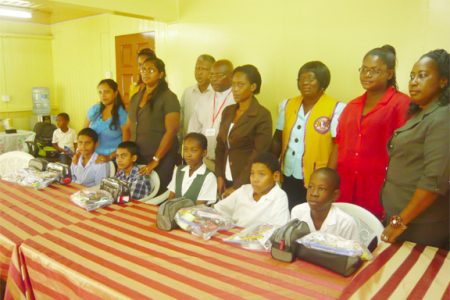 The students with their hampers are flanked by regional officials and members of the New Amsterdam Lions Club