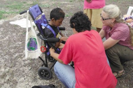 Two volunteers interact with a special needs child during the outreach