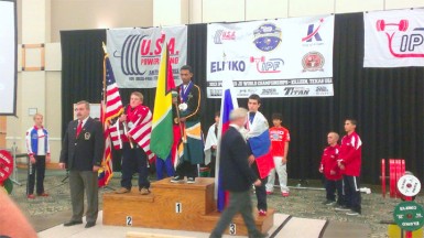 IT’S OFFICIAL! Gumendra Shewdas atop the podium is now officially Guyana’s youngest ever World Champion in any sport after being crowned World Champion of the 53kg class in the IPF World Juniors and Sub Juniors Men’s Championships in Killeen, Texas yesterday. The new world champion is flanked by USA’s Dalton La Coe (left) and Russia’s Alexei Kulakov.