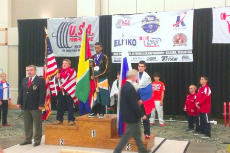 IT’S OFFICIAL! Gumendra Shewdas atop the podium is now officially Guyana’s youngest ever World Champion in any sport after being crowned World Champion of the 53kg class in the IPF World Juniors and Sub Juniors Men’s Championships in Killeen, Texas yesterday. The new world champion is flanked by USA’s Dalton La Coe (left) and Russia’s Alexei Kulakov.