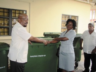 Overseer, Buxton/Foulis NDC Cherlyn Herod (second from right) uplifts the bins from Minister in the Ministry of Local Govern-ment and Regional Development Norman Whittaker. (GINA photo) 