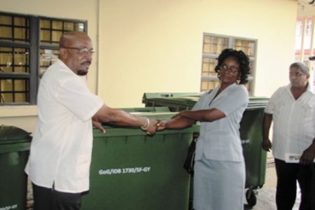 Overseer, Buxton/Foulis NDC Cherlyn Herod (second from right) uplifts the bins from Minister in the Ministry of Local Govern-ment and Regional Development Norman Whittaker. (GINA photo)
