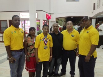 World Champ! 53kg sub junior world champion, Gumendra Shewdas is flanked by his parents and members of the GAPF upon arrival at the Cheddi Jagan International Airport last night. 