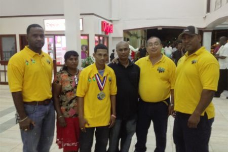 World Champ! 53kg sub junior world champion, Gumendra Shewdas is flanked by his parents and members of the GAPF upon arrival at the Cheddi Jagan International Airport last night.