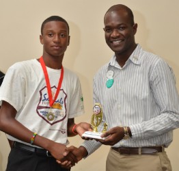 Renaldo Mohammed receives his trophy from Sandals Foundation representative OBrian Heron - WICB Media photo