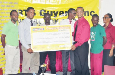 Courts Marketing Manager Pernell Cummings (second from left) presents a cheque symbolic of the $1.8M sponsorship to AAG President Aubrey Hutson while Olympian Winston George (centre), Cleveland Thomas (left), Tyshon Bentinck (second from right) and Courts PR and Marketing Officer Kester Abrams and another representative look on.  