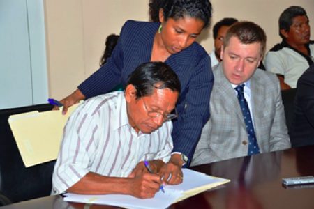 Hururu’s Toshao, Winsbert Benjamin signs the lease agreement between his community and Bauxite Company of Guyana Inc., (BCGI). (GINA photo)