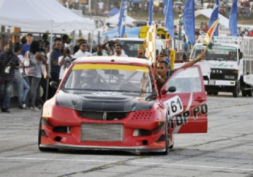 Champion Race car driver, Kevin Jeffrey waves the chequered flag after completing his second victory on the Group 4 category yesterday at the GMR&SC meet at the South Dakota Circuit. (Orlando Charles photo) 