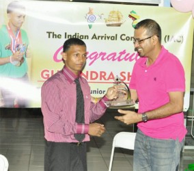 Minister of Natural Resources and the Environment, Robert Persaud rewards Gumendra Shewdas with a plaque for his historic feat at  the World Sub Juniors and Juniors Championships in Killeen, Texas last month where he became Guyana‘s youngest world power lifting champion. (Orlando Charles photo) 