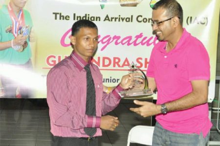 Minister of Natural Resources and the Environment, Robert Persaud rewards Gumendra Shewdas with a plaque for his historic feat at  the World Sub Juniors and Juniors Championships in Killeen, Texas last month where he became Guyana‘s youngest world power lifting champion. (Orlando Charles photo)
