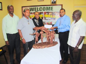 Minister of Culture, Youth and Sport Dr. Frank Anthony (second from right) hands over the  cheque to sculptors Philbert Gajadhar (centre) and Winslow Craig (second from left), as Director of Culture, Dr James Rose (right) and Permanent Secretary Alfred King look on. (GINA photo)  