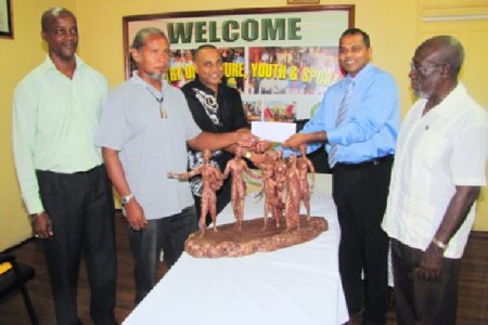 Minister of Culture, Youth and Sport Dr. Frank Anthony (second from right) hands over the  cheque to sculptors Philbert Gajadhar (centre) and Winslow Craig (second from left), as Director of Culture, Dr James Rose (right) and Permanent Secretary Alfred King look on. (GINA photo)
