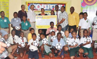 Managing Director of Courts Guyana Incorporated Clyde de Haas handing over sponsorship cheque to Petra Organization Co-Director Troy Mendonca as fellow executives and students from the participating schools look on. 