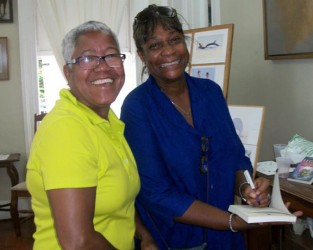  Maureen Marks-Mendonca (right) autographing a copy of her book for a fan.