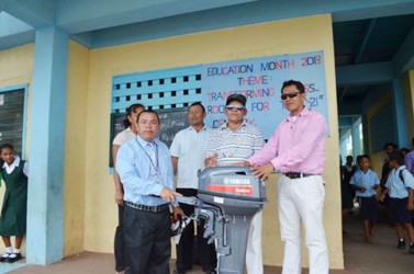 Regional Vice Chairman of Region One Fermin Singh (second from right) presenting the 15- horsepower engine to District Education Officer, Ignatius Adams (extreme right) while the head teacher of the St. Nicholas Primary school (left) looks on. (Government Information Agency photo)