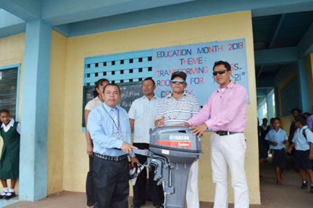 Regional Vice Chairman of Region One Fermin Singh (second from right) presenting the 15- horsepower engine to District Education Officer, Ignatius Adams (extreme right) while the head teacher of the St. Nicholas Primary school (left) looks on. (Government Information Agency photo)