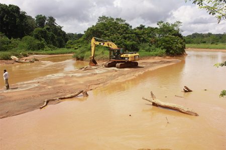 An excavator for mining crossing the silted Konawaruk River recently