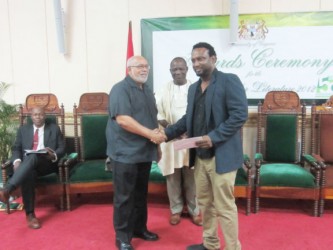 Ruel Johnson  (right) receiving his prize from President Donald Ramotar. At centre is UG Vice-Chancellor Jacob Opadeyi.