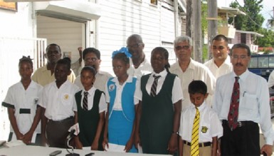  Minister of Finance Dr Ashni Singh (second, left in back row) poses with the bursary awardees, Adrian Benjamin of Benjamin’s Bakery (left, back row) and government functionaries. (GINA photo) 