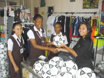 Receiving balls on behalf of the club from Store Manager Romona Arthur is Aaliyah Stanley while team mates Shaunna Taylor (left) and Cindy McPherson look on.  