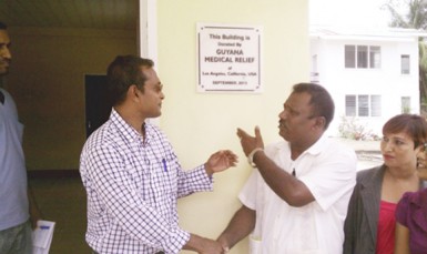 GMR Inc chief officer Sharir Chan (left) and Region Two Chairman Parmanand Persaud shake hands, while another representative looks on, after unveiling a plaque to mark the presentation of a newly-built VIA clinic at Charity. 