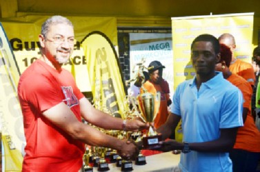 Guyana’s best 10k road runner Cleveland Forde receives his first place prize from Clyde De Haas, Courts Managing Director.