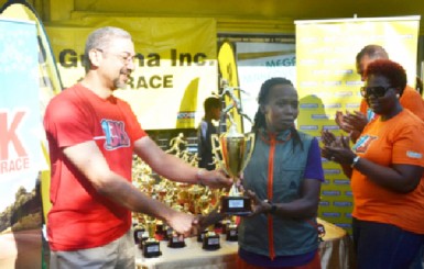 Women’s champion Euleen Josiah-Tanner collected her first place trophy from Courts Managing Director Clyde De Haas yesterday morning after the road race. 