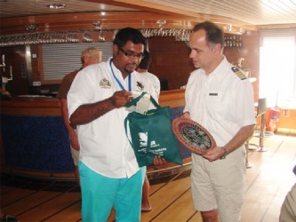 Minister of Tourism Irfaan Ally presents Captain of the National Geographic Explorer cruise ship Oliver Kruess with a token.