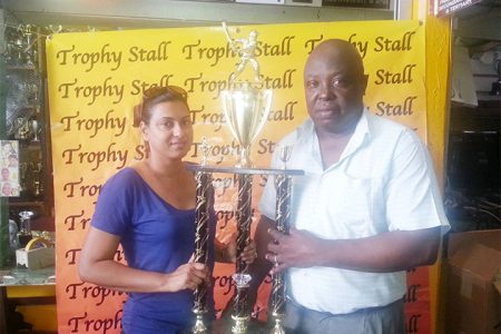 Devi Sunich, wife of Managing Director of Trophy Stall, Ramesh Sunich (left), hands over the first place trophy to first vice-president of the GSCL Inc Ian John.
 