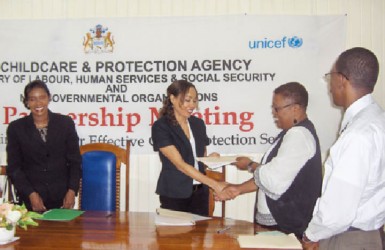 Forward Guyana Director Chantalle Haynes shakes hands with head of the Child Care and Protection Agency Ann Greene while receiving a copy of the Memorandum of Understanding signed to formalise the partnership for the operation of a Child Advocacy Centre, which is to begin operation next month. Looking on are Human Services Minister Jennifer Webster and ChildLink Inc Director Kwame Gilbert (Forward Guyana photo)