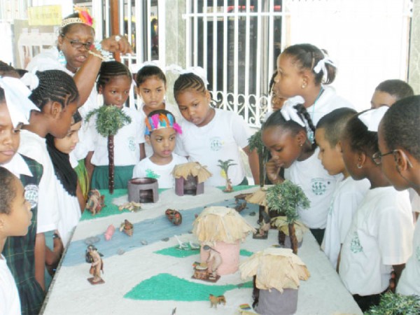 Mae’s students viewing a miniature Amerindian village at an exhibition held at the school in observance of Amerindian Heritage Month yesterday. (Photo by Arian Browne) 
