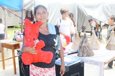 A woman displays a stuffed toy she made 