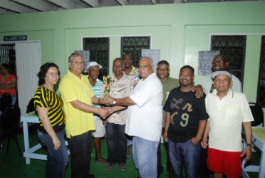 Proprietor of Living Clean Grocery and Variety Store Ramao Paul (left) hands over the winning trophy to skipper Edmond Sammy of Sammy’s Six in the presence of other team members. Paul’s wife Charmayne Paul is on his right. 