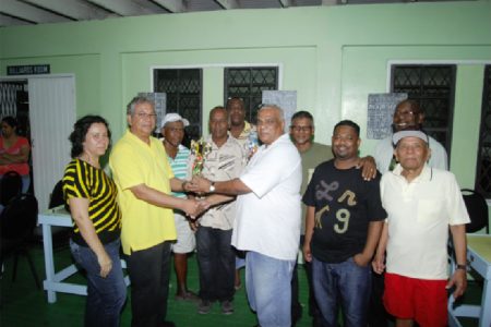 Proprietor of Living Clean Grocery and Variety Store Ramao Paul (left) hands over the winning trophy to skipper Edmond Sammy of Sammy’s Six in the presence of other team members. Paul’s wife Charmayne Paul is on his right.