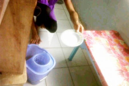 A parent bailing water out of the flooded classroom using a plate    