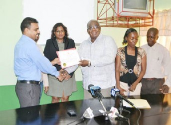 Chairman of the Board of Industrial Training, Clinton Williams (third from left) handing over the Apprenticeship licence to Barama’s Head of Corporate Affairs and Forest Planning,  Mohindra Chand. (GINA photo)
