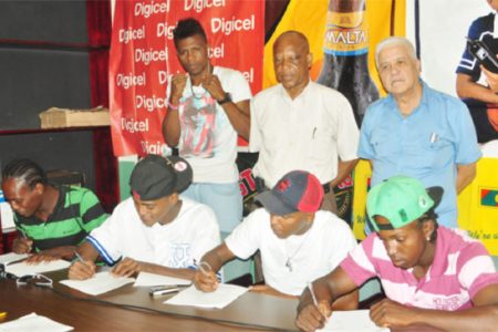 Some of the boxers that will take the ring on the 30th edition of the Guyana Fight Night Pro Am card on October 30 affixing their signature to their respective contracts yesterday. From right is Richard Williamson, Dexter Marques,Kishawn Simon, Edmond Declou (standing) and David Thomas (Orlando Charles photo) 
