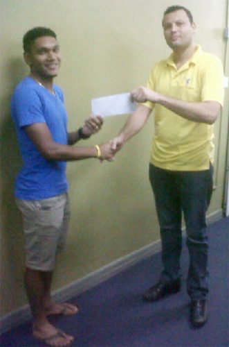National cyclist, Alanzo Greaves receiving his sponsorship cheque from Accountant of Bounty Farm Limited, Roger Perriera to aid in purchasing a pair of Zipp 404 Carbon Wheels.
