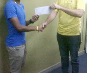 National cyclist, Alanzo Greaves receiving his sponsorship cheque from Accountant of Bounty Farm Limited, Roger Perriera to aid in purchasing a pair of Zipp 404 Carbon Wheels.