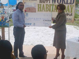 HfHG National Director Rawle Small (left) collects the symbolic cheque for $1 million from a GT&T representative