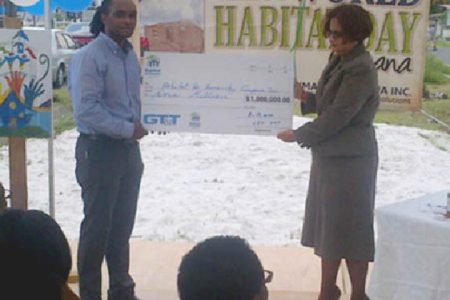 HfHG National Director Rawle Small (left) collects the symbolic cheque for $1 million from a GT&T representative