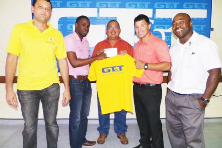 Customer Service Representative of GT&T, Quinsbert Tyndall (second from left) presenting GRFU head, Peter Green with a $500,000 cheque to aid the ruggers with their airfare and accommodation for the NACRA Sevens next month in the Cayman Islands.
